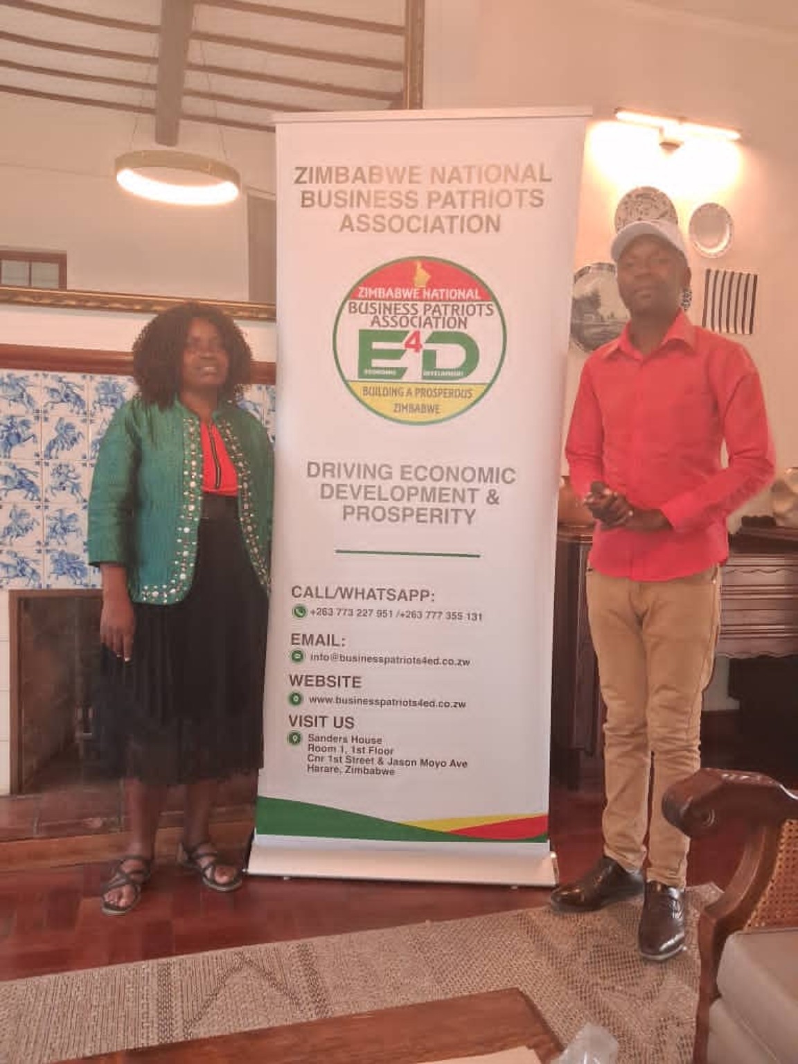 Two people standing beside an association banner.