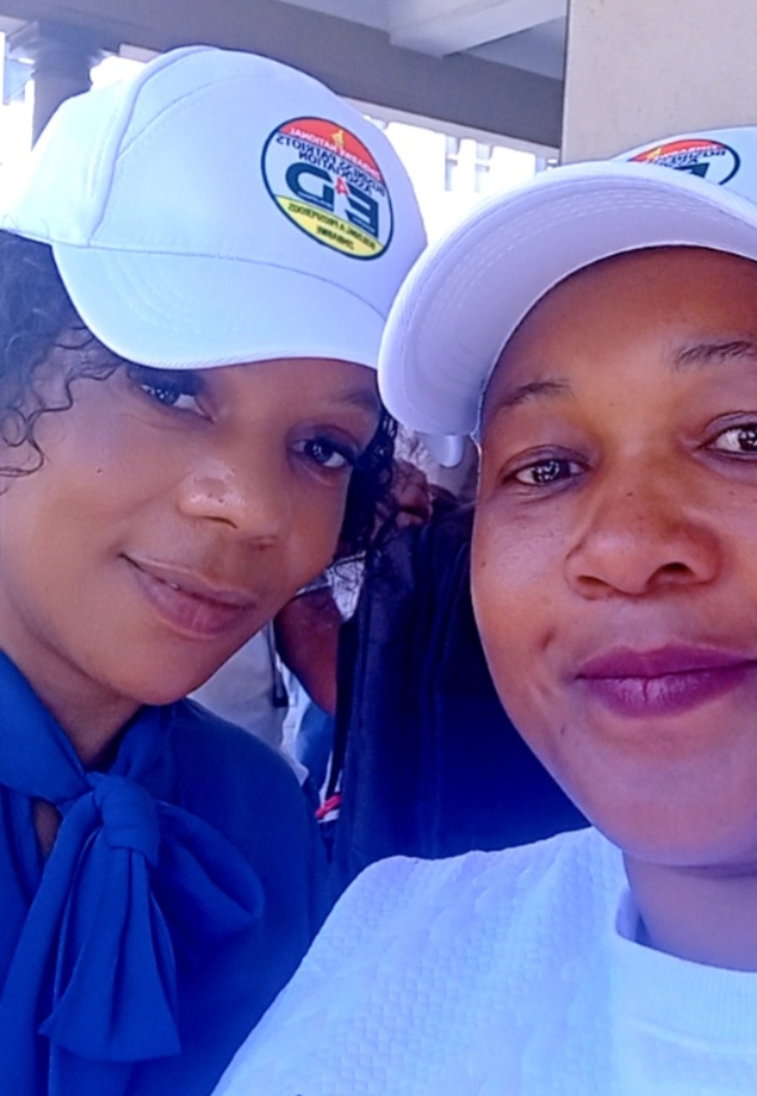 Two people wearing association-branded caps.