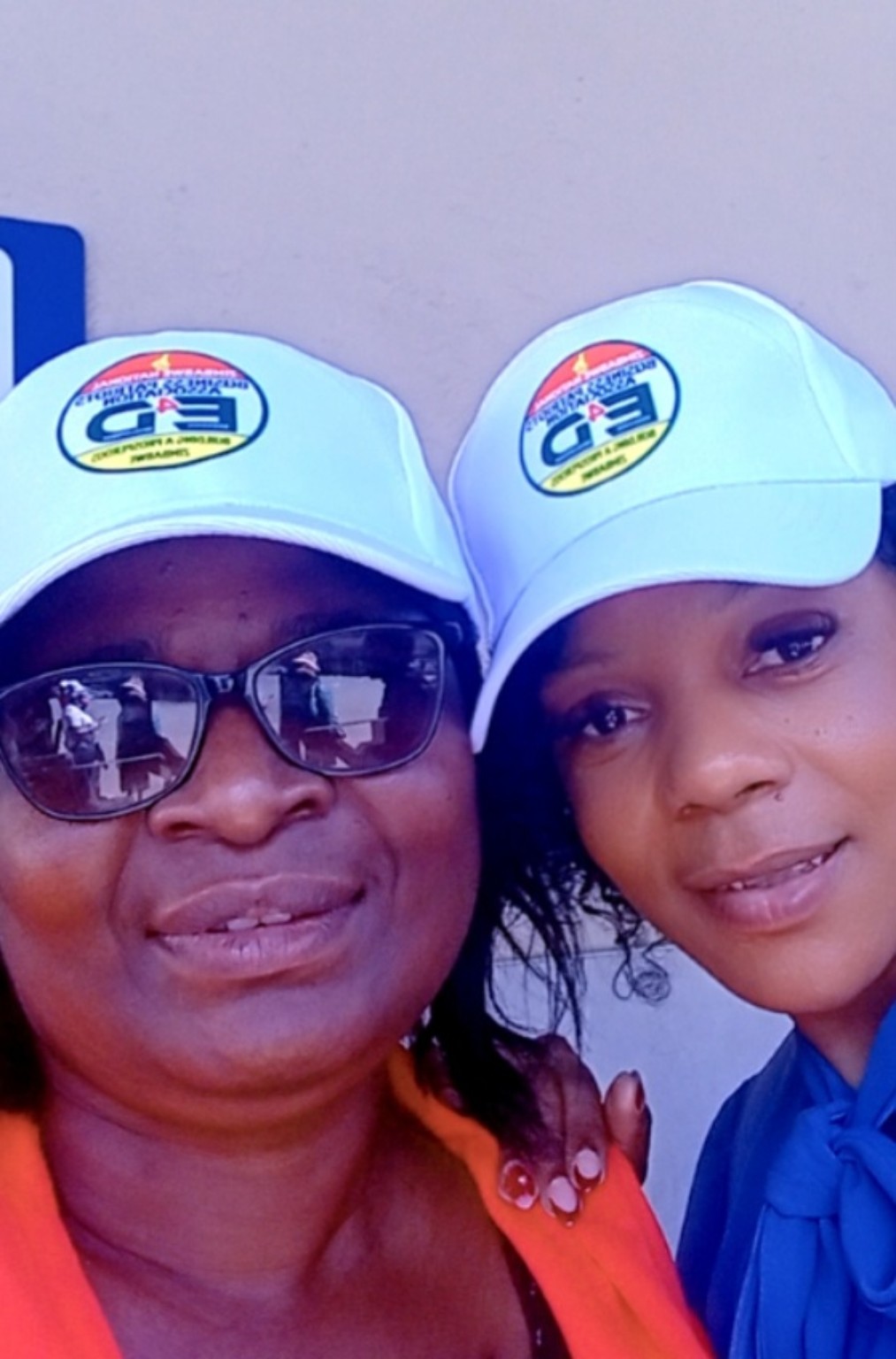 Two people wearing association-branded caps.